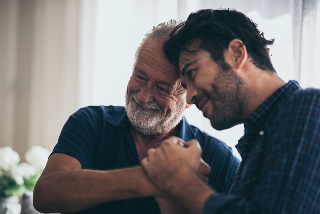 Men holding hands and smiling together.